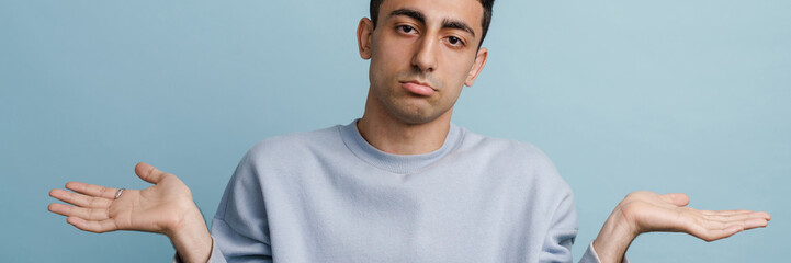 Obraz premium Young middle eastern man holding copyspace and looking at camera