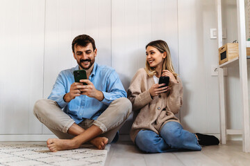 Happy young couple, woman and man hugging, using smartphone together. Social media concept.