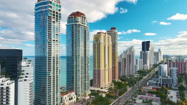 Sunny Isles Beach city with heavy urban traffic and expensive highrise hotels and condo buildings on Atlantic ocean shore. American tourism infrastructure in coastal southern Florida