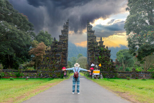 Tourist woman with backpack and hat on vacation walking through the Hindu temple in Bali Indonesia, Handara gate.