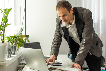 Frustrated dazed caucasian man, company employee, product manager, ceo, sitting at workplace in the office, looking at financial documents in surprise, dissatisfied with the result of work