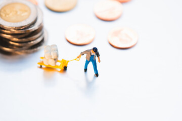 High angle view of miniature people pulling cargo with stack coins background using for logistic, business and financial concept