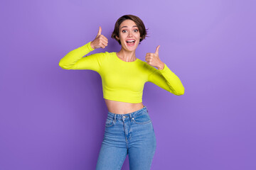 Portrait of astonished gorgeous lady hands fingers demonstrate thumb up approval isolated on purple...