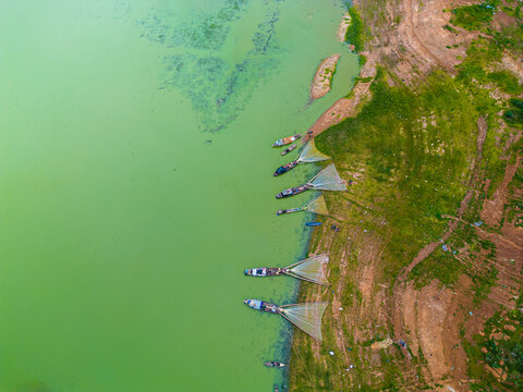 Aerial view of Ben Nom fishing village, a brilliant, fresh, green image of the green algae season on Tri An lake, with many traditional fishing boats anchored.