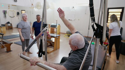 Pilates Coach helping Senior man to exercise in Pilates Studio, group physiotherapy session with...