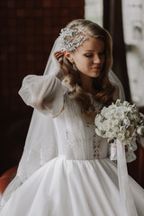 portrait of a blonde bride in a wedding dress with sleeves and a bouquet of flowers in her hands © Vasil