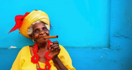 Fototapete Havana Colorful portrait of an old picturesque cuban woman smiling and smoking a cigar, blue wall panoramic background with copy-space, travel and tourism in Cuba header