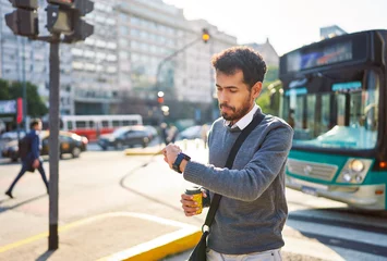 Foto op Plexiglas young adult latin american businessman walking down the street looking at his watch through the streets of Buenos Aires © oscargutzo