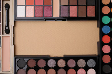 Frame made of beautiful eye shadow palettes on beige background, flat lay. Space for text