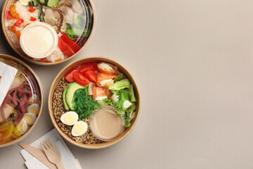 Tasty food in containers with wooden knife and fork on light grey table, flat lay. Space for text