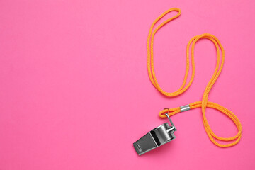 One metal whistle with cord on pink background, top view. Space for text