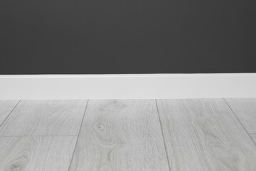 White plinth on laminated floor near black wall indoors