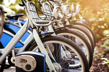 Bike Sharing System. Electric Bicycles or e bikes Charging in Public Parking lot. Modern Blue Bikes with Basket  for Rental Service. Eco Transport concept - obrazy, fototapety, plakaty