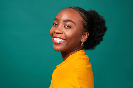 Beautiful Black woman smiles, studio teal background, fashion lifestyle portrait