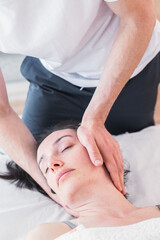 Fototapeta na wymiar Therapist doing a session with localized massage in the region of the skull with the application of small, gentle pressures to improve the patient's state of health. CranioSacral Therapy.