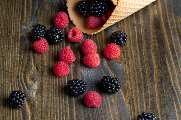 Red ripe raspberries with waffle cups on a black table