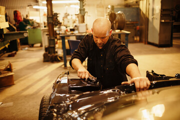 Mature man working on a car in the workshop