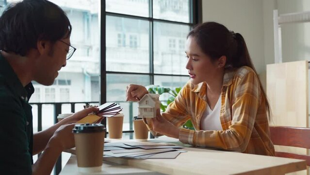 teamwork working on home renovation makeover new project asian male and female creative designer checking colour material scheme and planing design discussion together at home office daylight