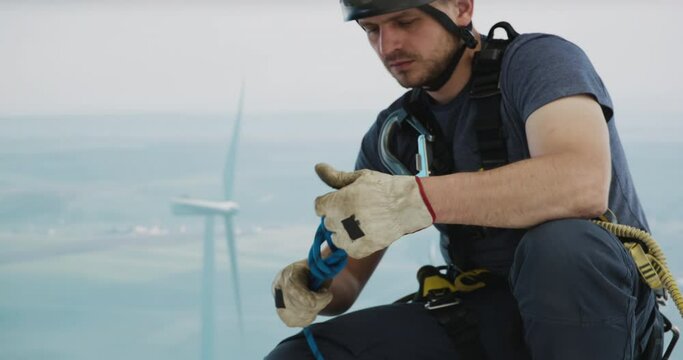 Engineer performing repairing and maintenance works on top of wind turbine nacelle house. Portrait of skilled professional worker working at high altitude 