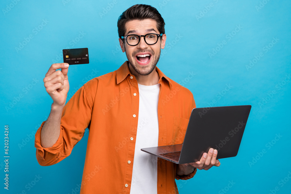 Aufkleber portrait of astonished positive person hold netbook showing debit card open mouth isolated on blue c