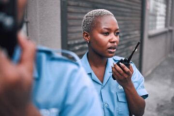 Security, walkie talkie and a police woman in the city during her patrol for safety or law enforcement. Radio, communication and service with an african female guard on a street in an urban town - obrazy, fototapety, plakaty