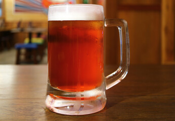 Closeup of a glass of chilled draft beer served on wooden table