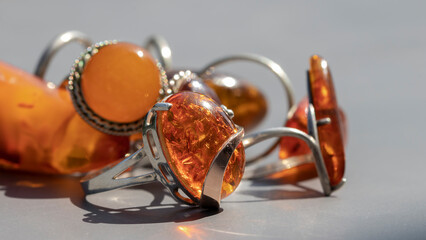 Different shiny Baltic amber rings in silver close up. Isolated vintage amber jewelry on a gray...