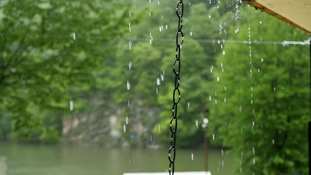 Drops of heavy rain drip from a canvas roof in a forest park. Falling drops and rain splashes in slow motion. Autumn heavy rain in the forest