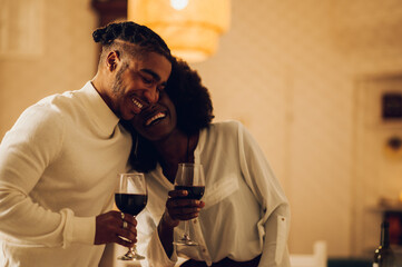 African american couple having a romantic date and hugging while drinking wine