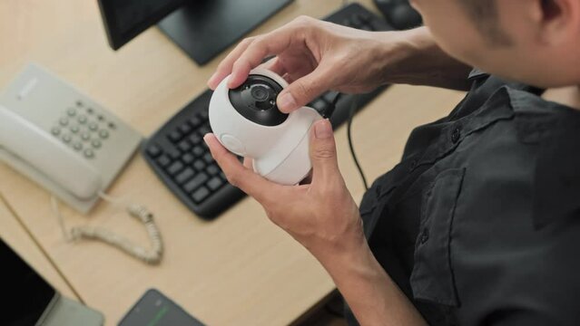 High angle view of guard in uniform connecting surveillance camera with mobile app on smartphone