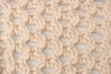 A fragment of beige knitted fabric, knitted from white sheep wool.
