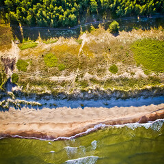 Scenic view down to the shore of curonian spit with green seawater and breaking waves.Vertical  Background with no people image.