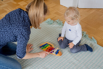 Mother and little child playing with toys, xylophone