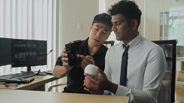 Medium shot of security guard instructing manager how to use mobile app using surveillance camera at workMedium shot of security guard instructing manager how to use mobile app using surveillance came