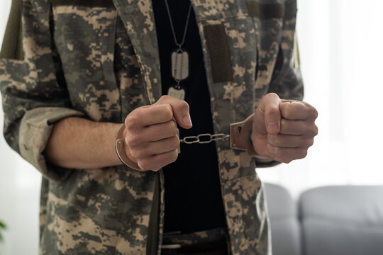 A handcuffed soldier behind the bars against a black background. Concept: court martial, refusal to mobilize, crime in the army. - Powered by Adobe