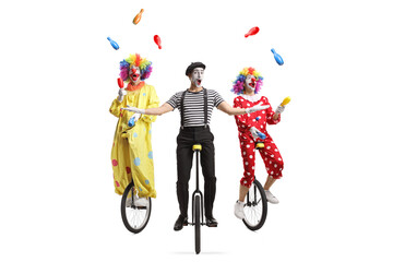Two clowns and a mime riding unicycles and juggling