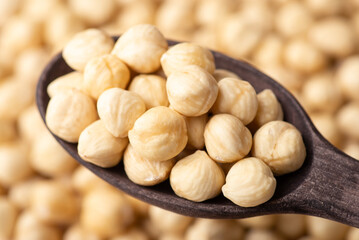 Dark wooden spoon with peeled hazelnuts. Fresh tasty hazelnuts close up