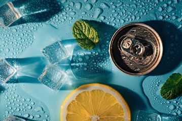 Fotobehang Creative summer composition with lemon slice, mint leaves, can of soda and ice cubes. Minimal lemonade drink concept. © Sofiia Tiuleneva
