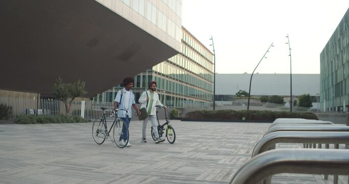 Two young entrepreneurs walk with a bicycle while talking in a financial district