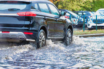 Flooding in the city after the rain. The car drives through a puddle in the pouring rain. Splashes...