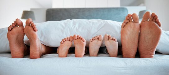Family feet, bed and blanket in closeup, parents or kids sleeping on holiday in morning, care and relax. Bedroom, people and sleep with mom, dad or children on vacation, home or break in hospitality