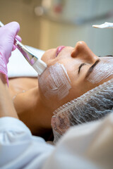 Professional beautician doing skin care procedures to woman client.