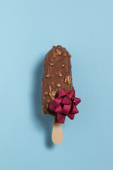 Ice cream covered with chocolate and almonds with a red bow on a blue background
