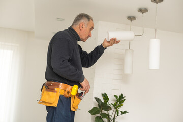 Electrician installs lamp lighting and spot loft style on ceiling