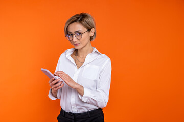 Fototapeta premium Confident beautiful woman wearing white official style shirt using mobile phone