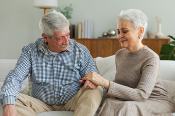 Senior adult mature couple in love holding hands at home. Mid age old husband and wife looking with tenderness love enjoying wellbeing. Grandmother grandfather together. Family moment love and care