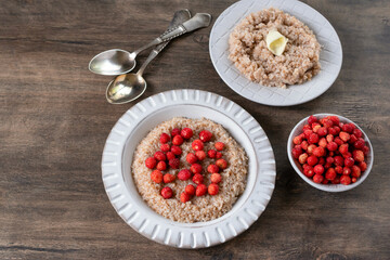 Spelled porridge for breakfast. Wheat porridge with strawberries. Seasonal summer wild berry. Healthy food.