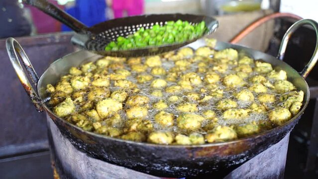 This is closeup shot of Frying Fritters with green chilling Indian oily food