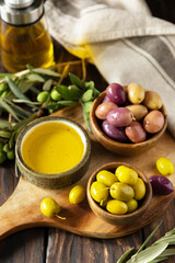 Freshly picked olives berries in wooden bowls and pressed oil served on old wooden boards.