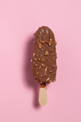 Ice cream covered with chocolate and almonds on pink background